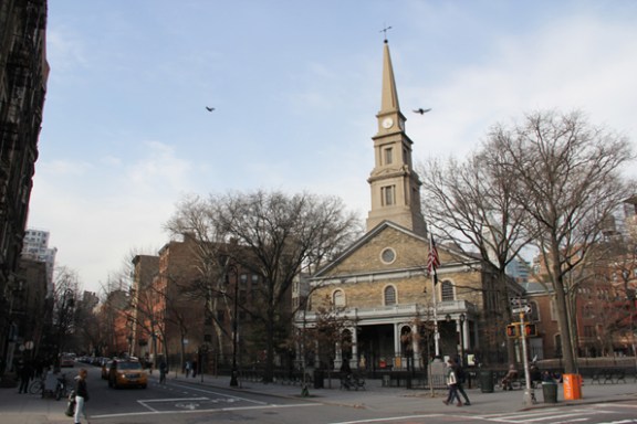 a church with a clock on the side of a road